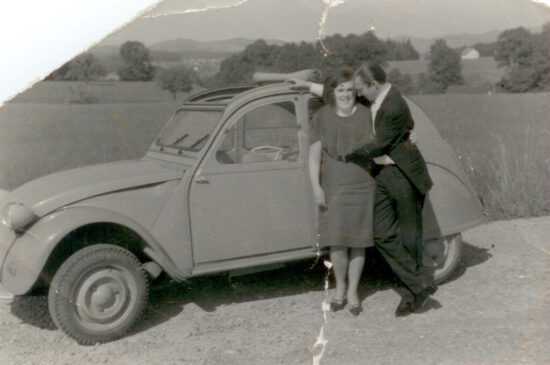 junges Ehepaar vor auto in schwarz weiss